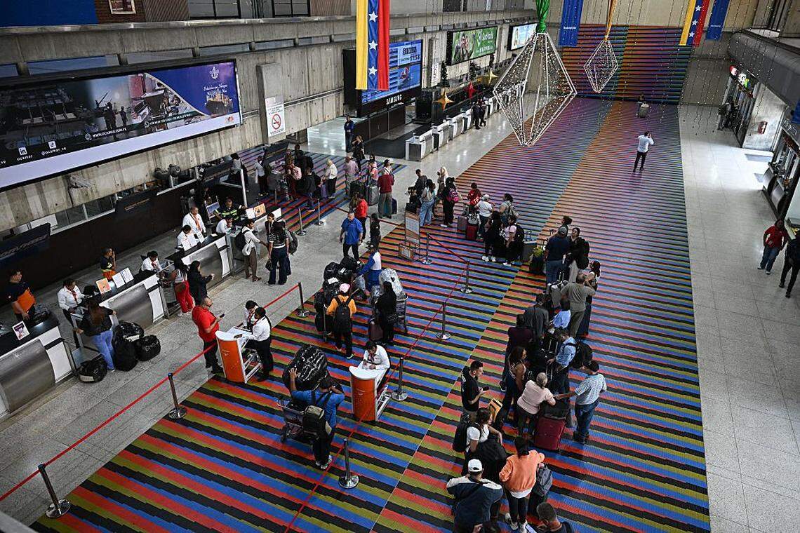 Passengers queue at counters at Simon Bolivar International Airport in Maiquetia, La Guaira State, Venezuela, on November 27, 2025. Venezuela's decision to ban foreign airlines that stopped flying to the Caribbean country over concerns about US military activity was branded "disproportionate" on Thursday as thousands of passengers scrambled to save their travel plans. (Photo by Federico PARRA / AFP via Getty Images)