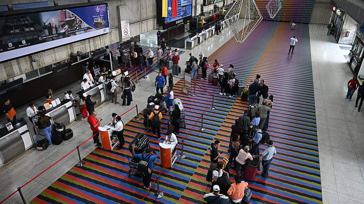 Passengers queue at counters at Simon Bolivar International Airport in Maiquetia, La Guaira State, Venezuela, on November 27, 2025. Venezuela's decision to ban foreign airlines that stopped flying to the Caribbean country over concerns about US military activity was branded "disproportionate" on Thursday as thousands of passengers scrambled to save their travel plans. (Photo by Federico PARRA / AFP via Getty Images)