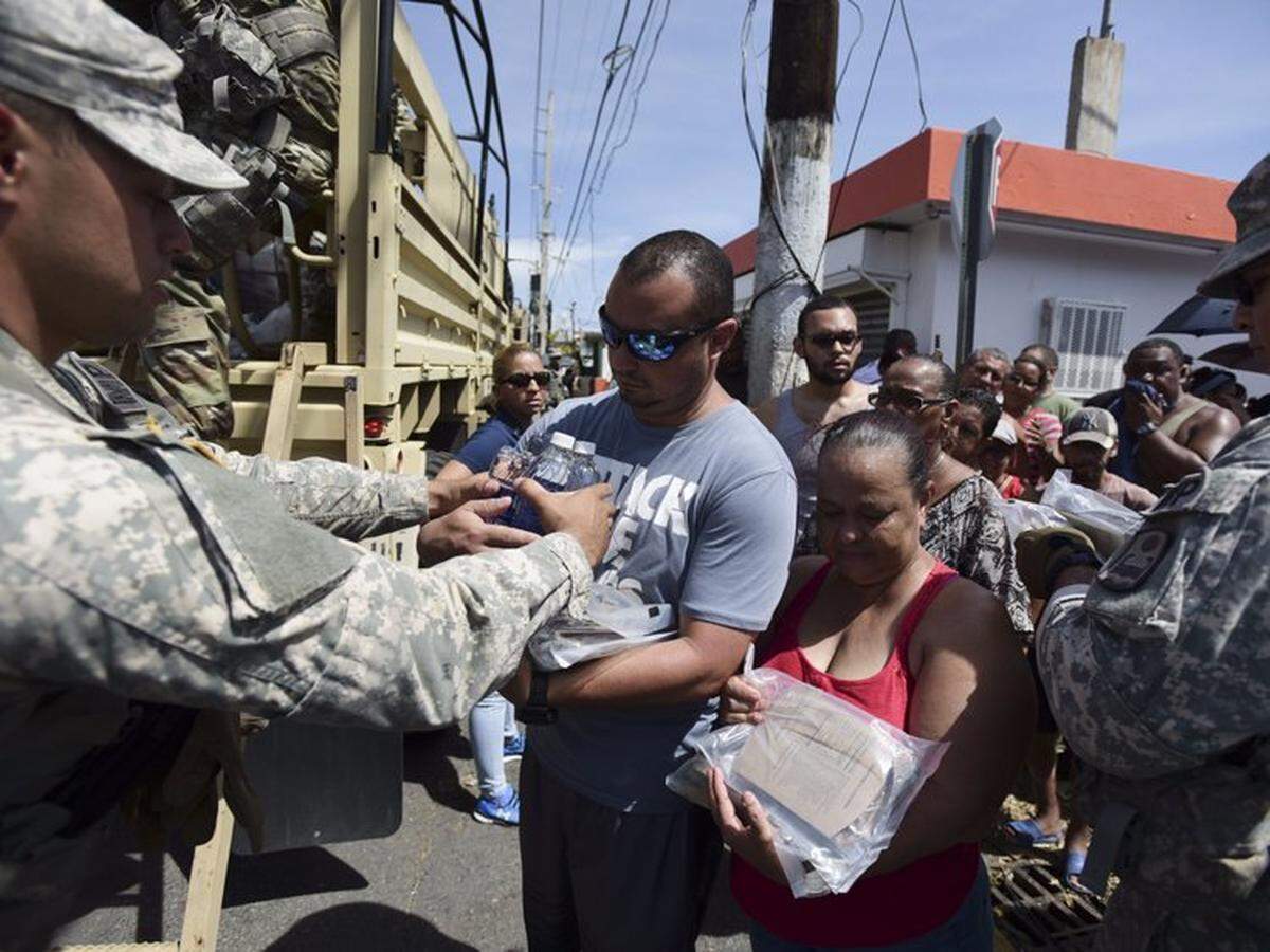 Miembros de la Guardia Nacional distribuyen agua y alimentos a los damnificados por el huracán María, en San Juan, Puerto Rico.