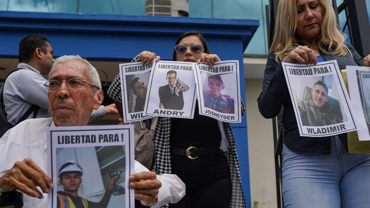 Walter Márquez, presidente de la Fundación El Amparo Internacional, una organización de derechos humanos y familiares de migrantes detenidos sostienen imágenes de migrantes venezolanos detenidos en la oficina del defensor del pueblo acompañados por familiares de venezolanos deportados por Estados Unidos a El Salvador.