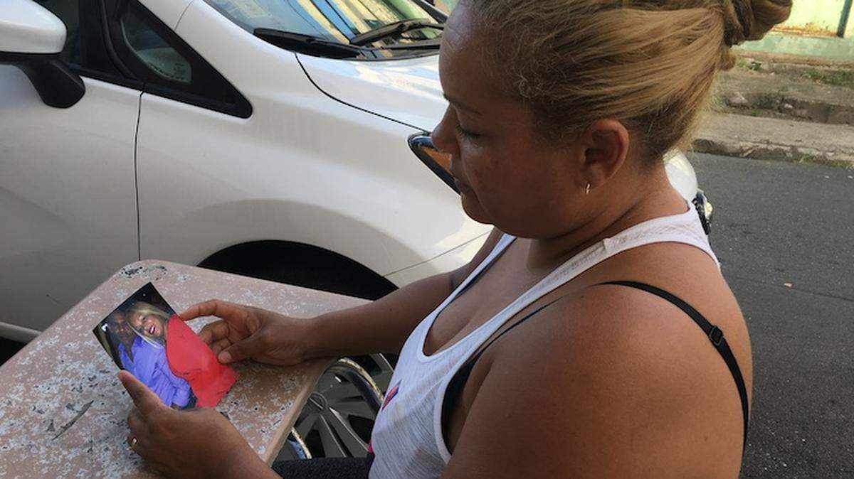 Audri Román frente a su casa en Barrio Obrero, Santurce, observa una foto donde aparecen ella y su esposo Johnny Santana.
