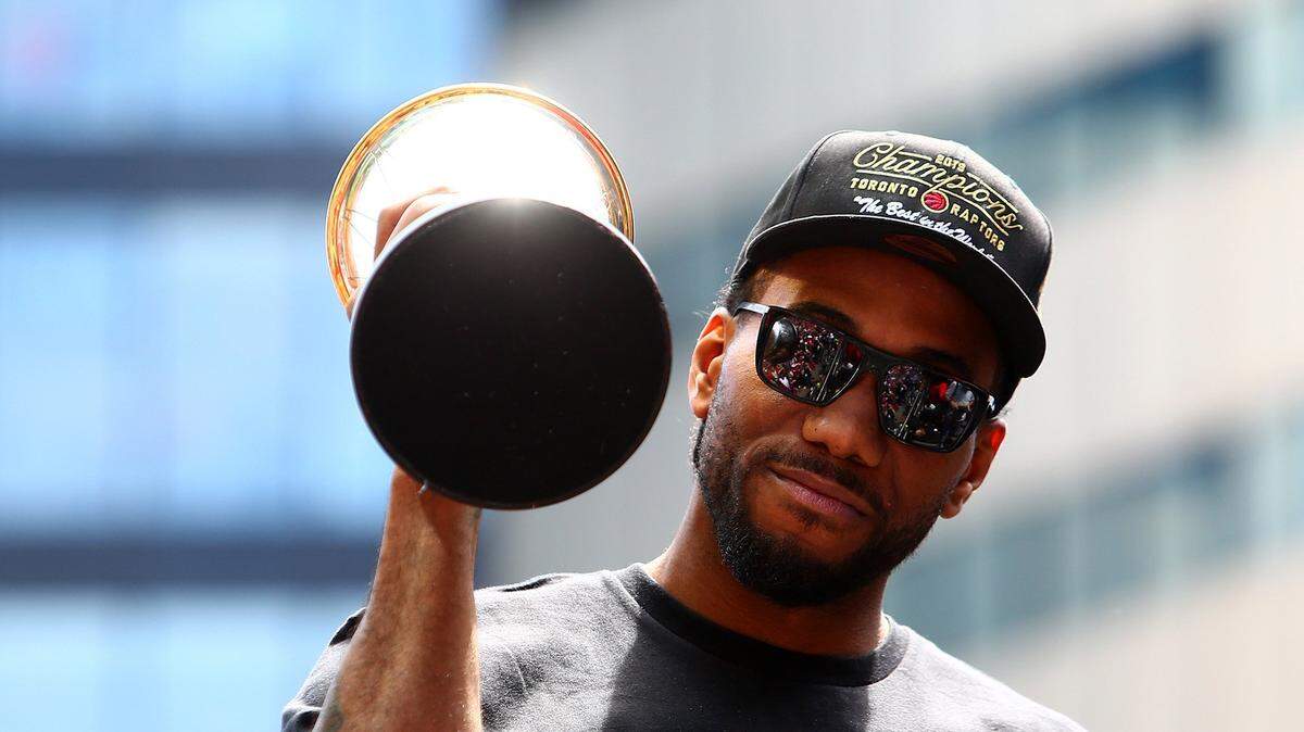 Kawhi Leonard sostiene el trofeo de Jugador Más Valioso en el desfile de los Raptors por Toronto el 17 de junio de 2019.
