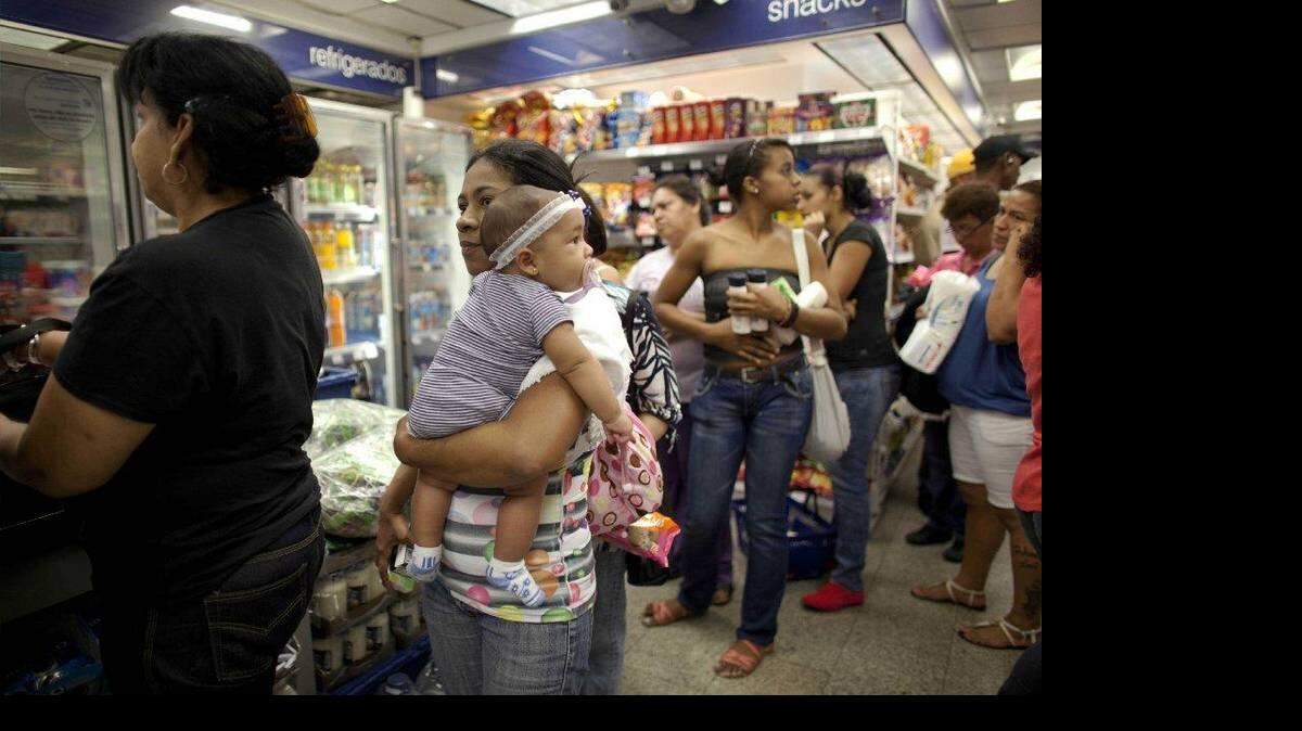 Milagro Álvarez carga a su hija de cinco meses mientras hace fila en una sucursal de la tienda Farmatodo de Caracas, Venezuela, el viernes 24 de octubre de 2014.