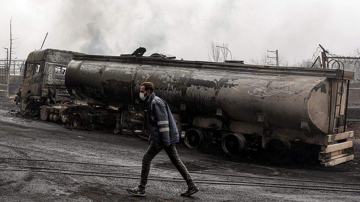 Un miembro de la defensa civil iraní camina junto a un vehículo cisterna de combustible destruido cerca de un incendio en curso luego de un ataque aéreo nocturno en la refinería de petróleo de Shahran en el noroeste de Teherán, el domingo 8 de marzo de 2026.