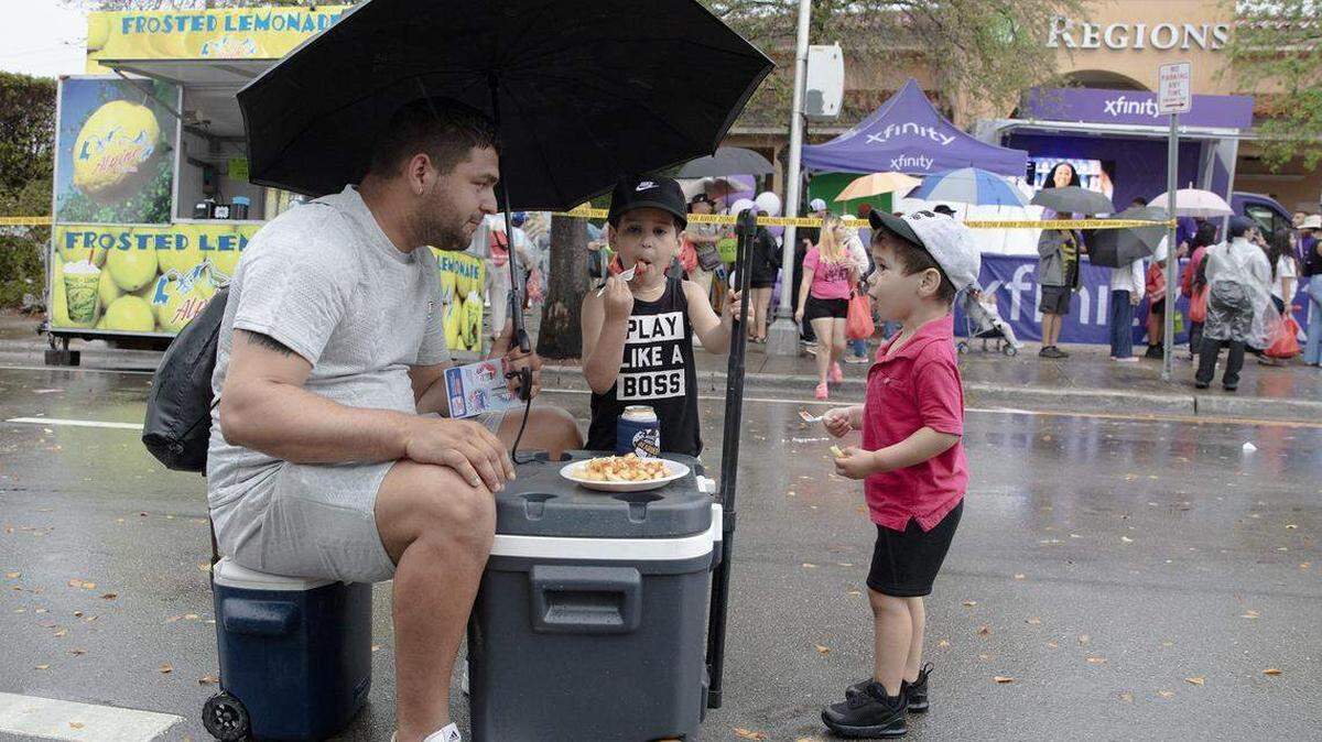 Alejandro Galindo comparte papas fritas con sus hijos, Ethan y Dylan, en medio de la calle 8 del SW durante el festival Calle Ocho, el domingo 15 de marzo de 2026, en La Pequeña Habana. ¿Será este el segundo fin de semana consecutivo pasado por agua?