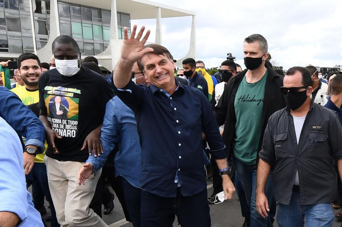 Brazil’s President Jair Bolsonaro greets supporters upon arrival at the Planalto Palace, his official workplace in Brasilia, on May 24, 2020, as deaths by the COVID-19 continue to rise.