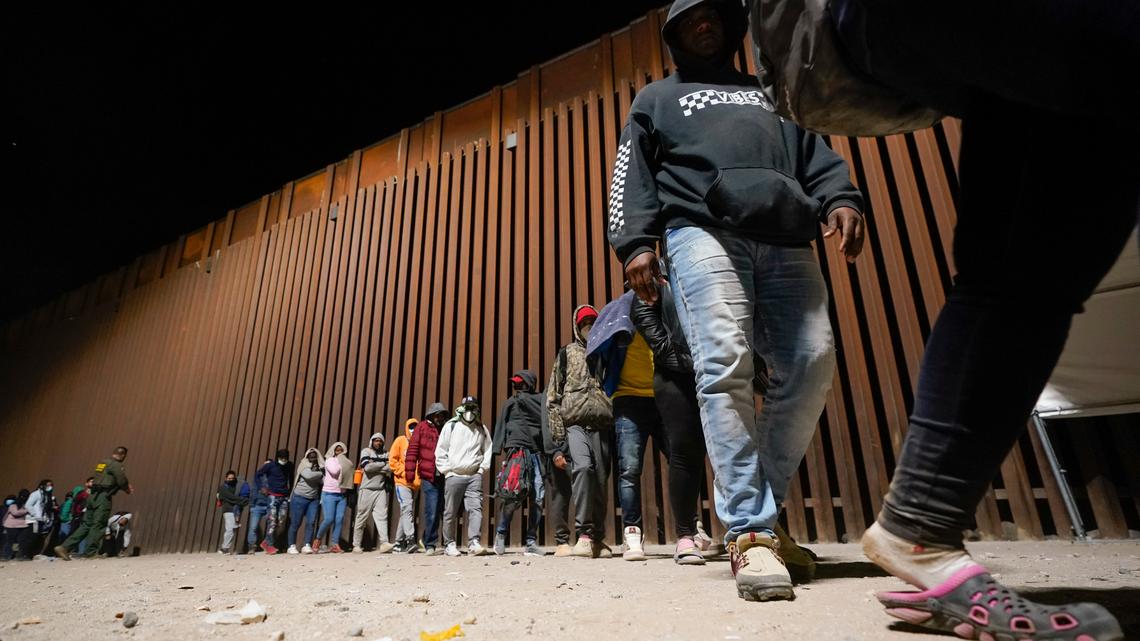 A group of migrants, mostly from Cuba, lines up to board a bus after crossing the border from Mexico and turning themselves in to authorities for asylum on Nov. 3, 2022, near Yuma, Arizona.