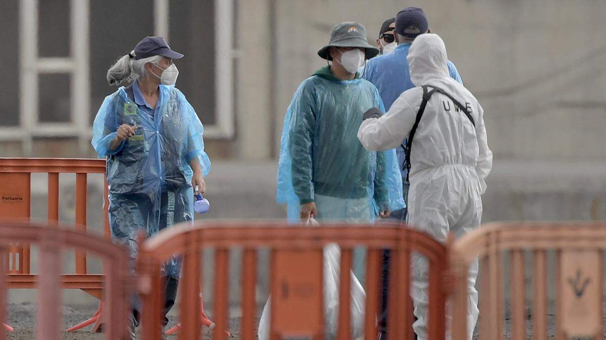 Pasajeros turcos del crucero con bandera neerlandesa MV Hondius, afectado por un brote de hantavirus, hablan con personal vestido con trajes de protección biológica mientras desembarcan en el puerto industrial de Granadilla de Abona, en la isla de Tenerife, en las Islas Canarias de España, el 10 de mayo de 2026.