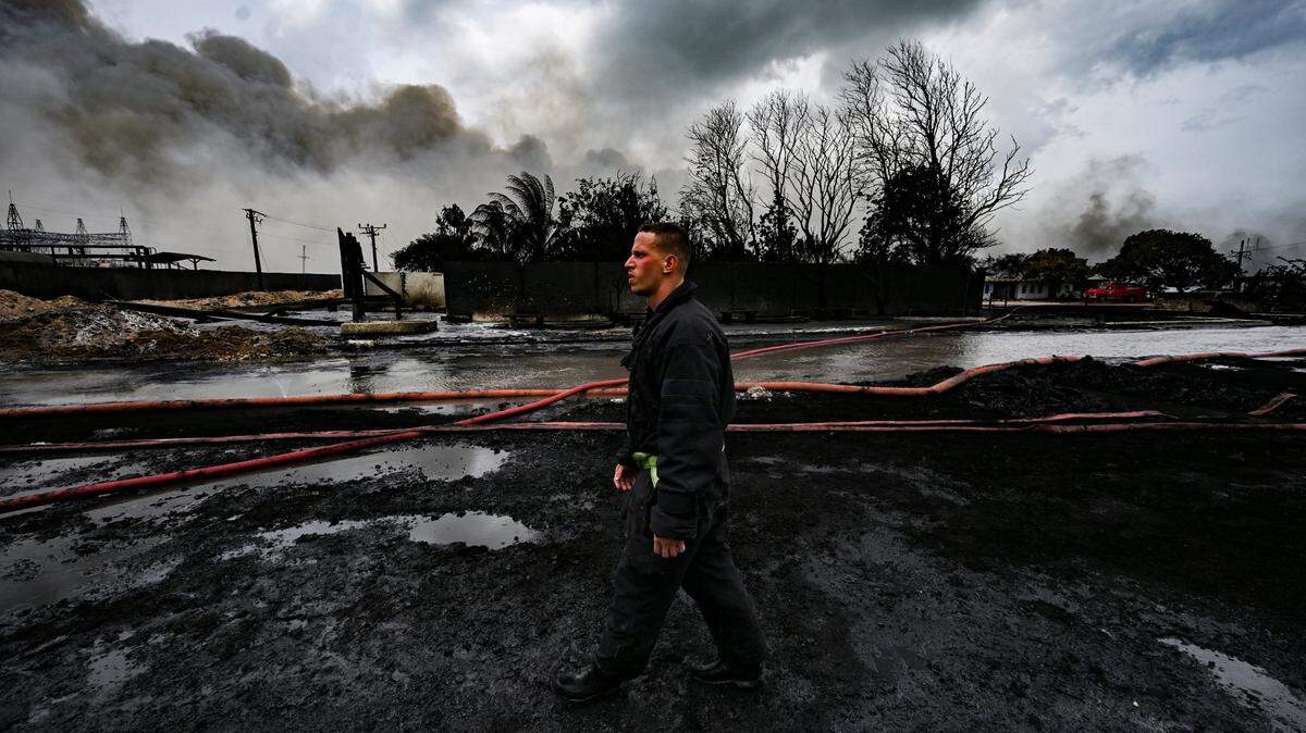 Un bombero camina en el sitio de un incendio mortal en una gran instalación de almacenamiento de petróleo en Matanzas, Cuba, el martes 9 de agosto de 2022. El incendio se desencadenó cuando un rayo golpeó uno de los ocho tanques de la instalación el viernes 5 de agosto. (Yamil Lage, foto pool vía AP)
