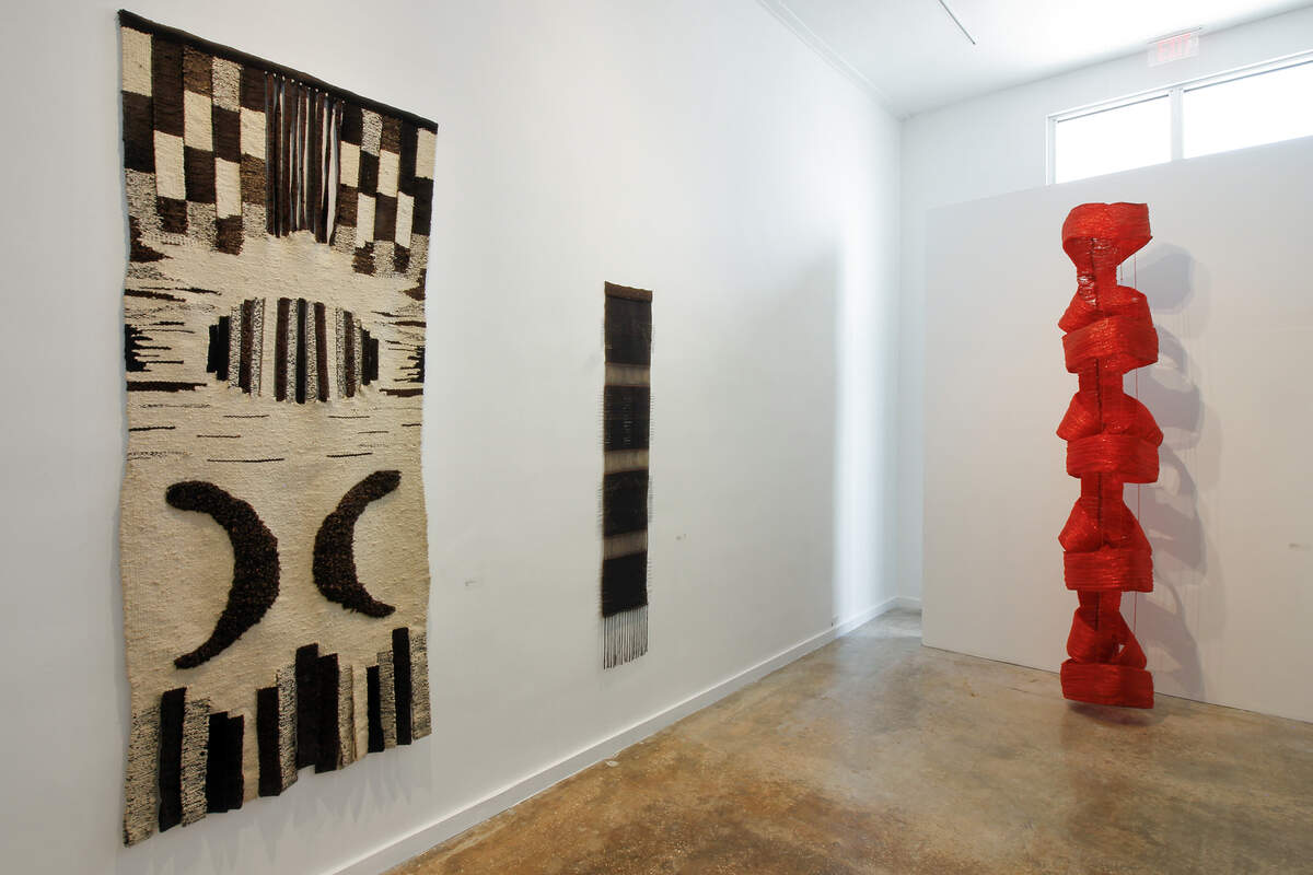 Vista Parcial. Stella Bernal de Parra. De izquierda a derecha: ‘Coloquio en blanco y negro’, 1975, lana virgen, 86 1/6 x 43 1/3 pulgadas. ‘Eclipse solar’, 1980, tapiz tejido plano. Urdimbre en hilo de algodón y varillas de cobre 86 1/6 x 43 ¼ pulgadas; ‘El gusarapo’, 1973, lana teñida y trama de celofán, alambre galvanizado, altura, 10 pies.