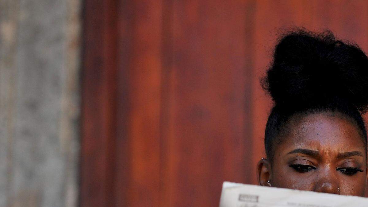 Una mujer fuma un cigarro mientras lee el periódico en una calle de La Habana, el 26 de noviembre de 2016, un día después de que el líder revolucionario cubano Fidel Castro muriera a los 90 años.