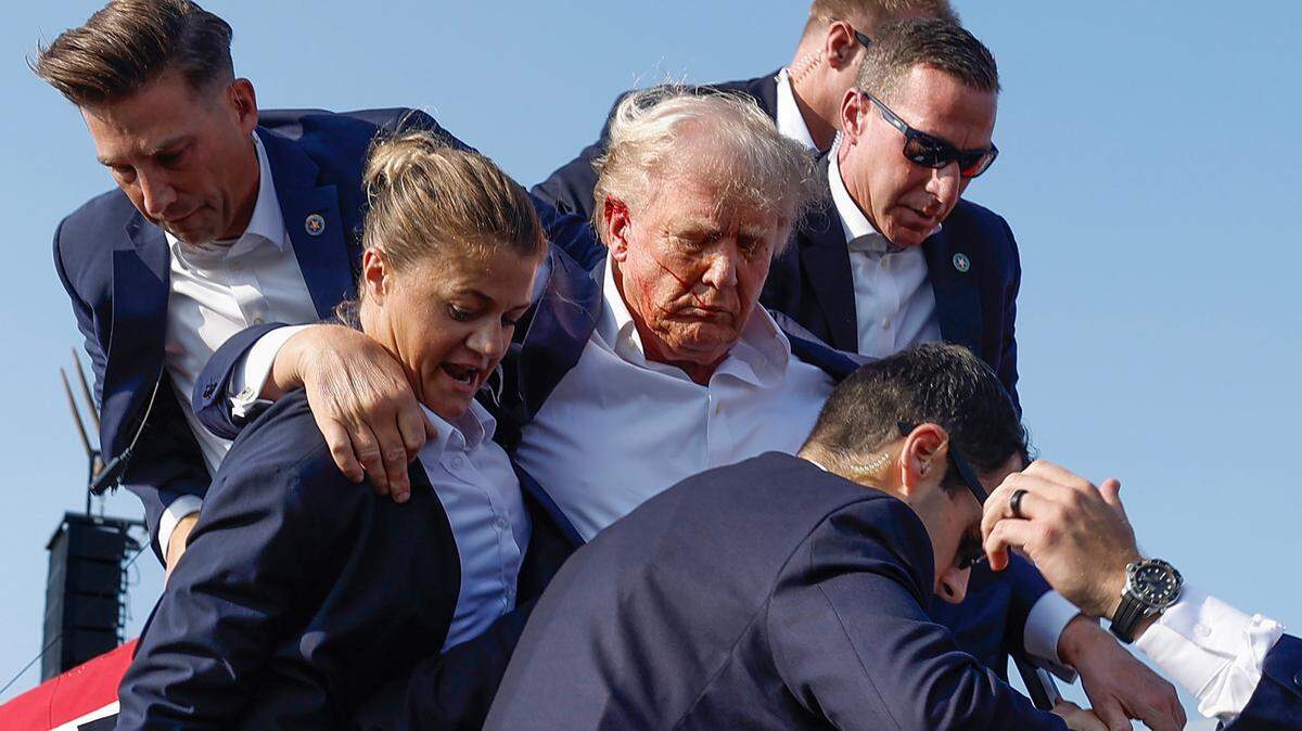 El ex presidente Donald Trump, visto con lo que parece ser sangre en la cara, rodeado de agentes del Servicio Secreto mientras es sacado del escenario en un acto de campaña en Butler Farm Show Inc., en Butler, Pennsylvania, el sábado 13 de julio de 2024.