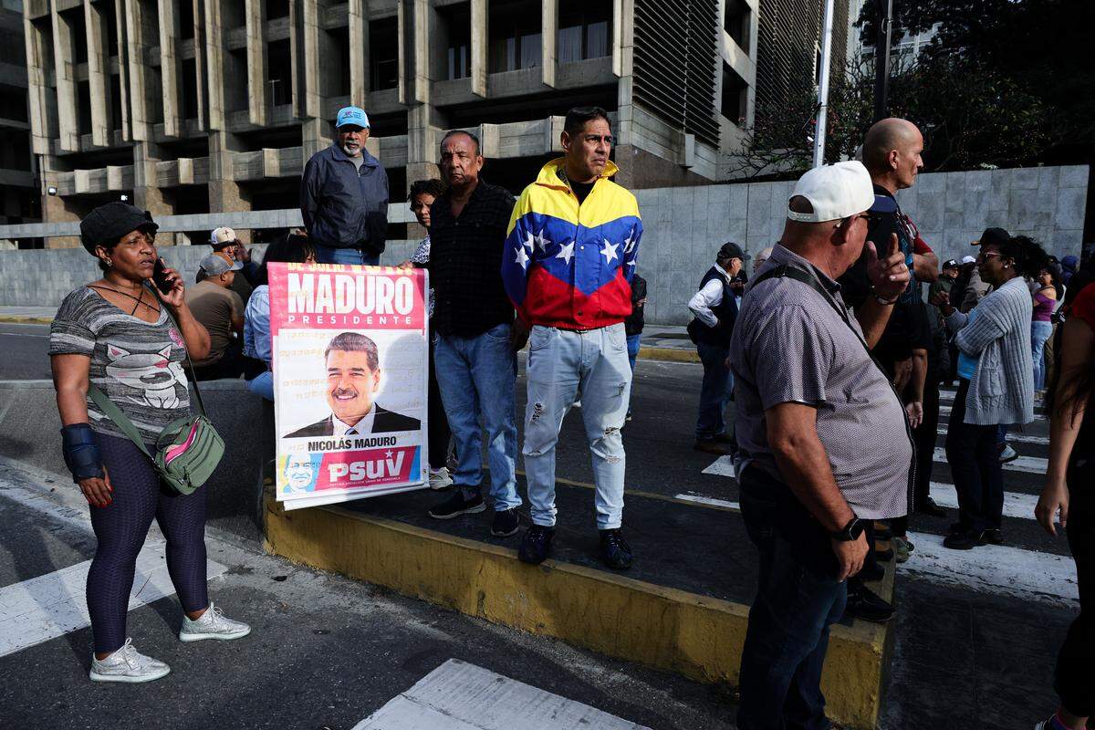 CARACAS, VENEZUELA - JANUARY 03: Supporters of Nicolas Maduro hold a poster with his image near Miraflores Palace after explosions and low-flying aircraft were heard and Maduro’s capture was confirmed on January 03, 2026 in Caracas, Venezuela. According to some reports, explosions were heard in Caracas and other cities near airports and military bases around 2 am. US President Donald Trump later announced that his country’s military had launched a “large-scale” attack on Venezuela and captured its President Nicolas Maduro and his wife. (Photo by Jesus Vargas/Getty Images)