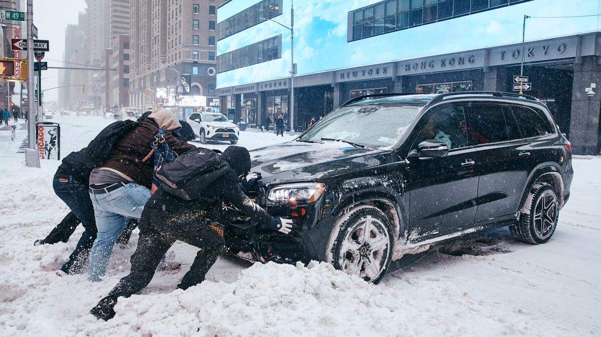 Un grupo de hombres ayuda a retirar un automóvil que quedó atascado en la nieve el 25 de enero de 2026 en la ciudad de Nueva York. Una tormenta invernal masiva está llevando temperaturas gélidas, hielo y nieve a casi 200 millones de estadounidenses.
