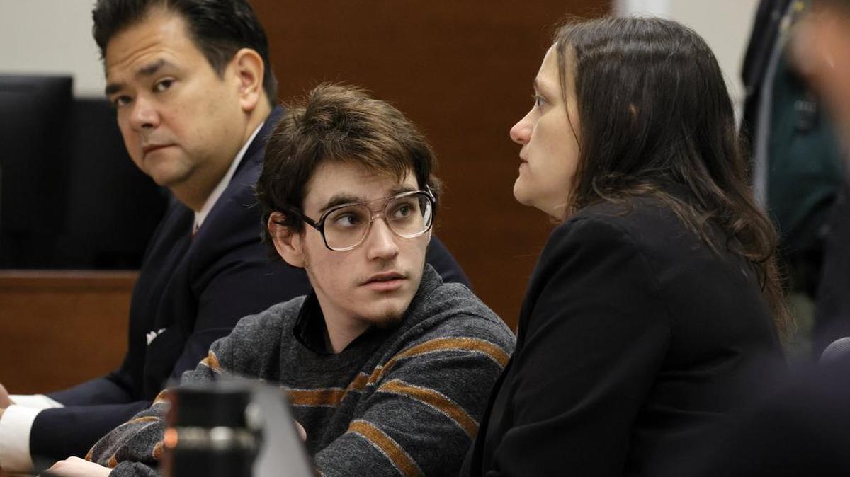 Nikolas Cruz, habla con la especialista en mitigación de sentencias Kate O’Shea, miembro del equipo de defensa, mientras el Asistente del Defensor Público David Wheeler se muestra a la izquierda durante la selección del jurado en la fase de penalización de su juicio en el Palacio de justicia en Fort Lauderdale el lunes 23 de mayo de 2022. (Amy Beth Bennett/South Florida Sun Sentinel vía AP)