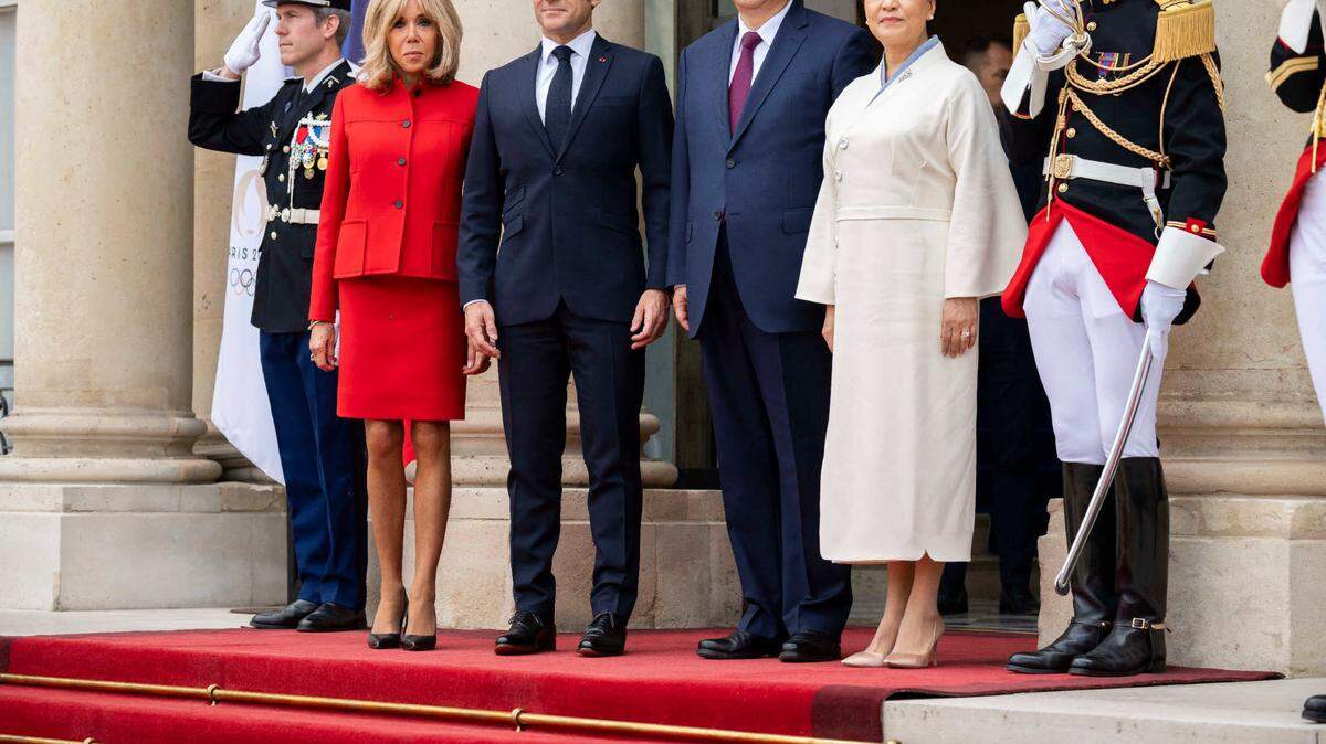El presidente de Francia Emmanuel Macron y su esposa Brigitte Macron (izq.) posan en el recibimiento en París al mandatario de China Xi Jinping y la primera dama Peng Liyuan, el 6 de mayo de 2024.