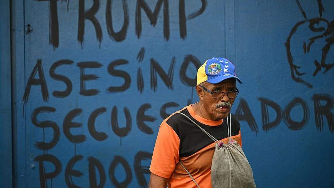 A man passes in front of anti-Trump graffiti during a rally in support of ousted Venezuelan President Nicolas Maduro and his wife, Cilia Flores, in Caracas on January 6, 2026. US forces killed 55 Venezuelan and Cuban military personnel during their stunning raid to capture Nicolas Maduro, tolls published by Caracas and Havana showed on January 6. (Photo by RONALDO SCHEMIDT / AFP via Getty Images)