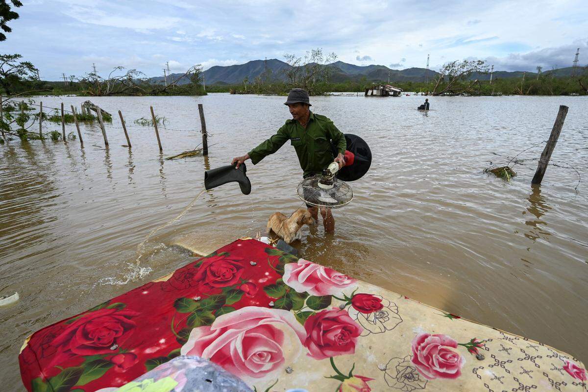 A farmer rescues his dog and some belongings from his flooded house after Hurricane Melissa passed through the town of San Miguel de Parada in Santiago de Cuba province on October 29, 2025. A powerful Hurricane Melissa made landfall in eastern Cuba on Wednesday, causing damage and flooding to homes and streets in Santiago de Cuba province, an AFP team on the ground reported. (Photo by YAMIL LAGE / AFP) (Photo by YAMIL LAGE/AFP via Getty Images)