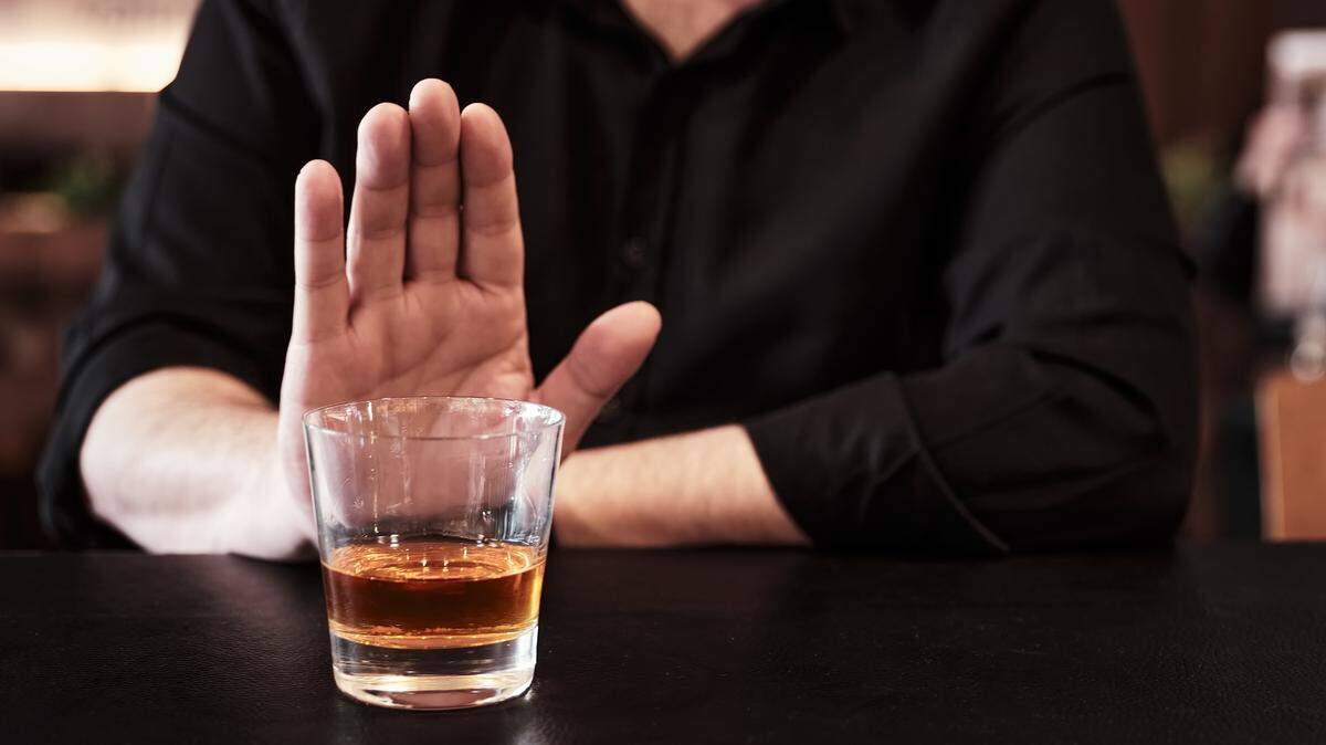 Man refuses or rejects to drink alcohol at the pub. Alcohol addiction treatment, sobriety and drinking problem.