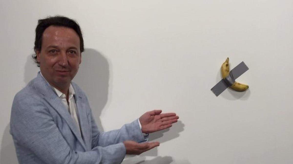 Gallerist Emmanuel Perrotin poses with “Çomedian,” a work by Italian artist Maurizio Cattelan that consists of a banana stuck to a wall at Art Basel in Miami Beach in 2019.