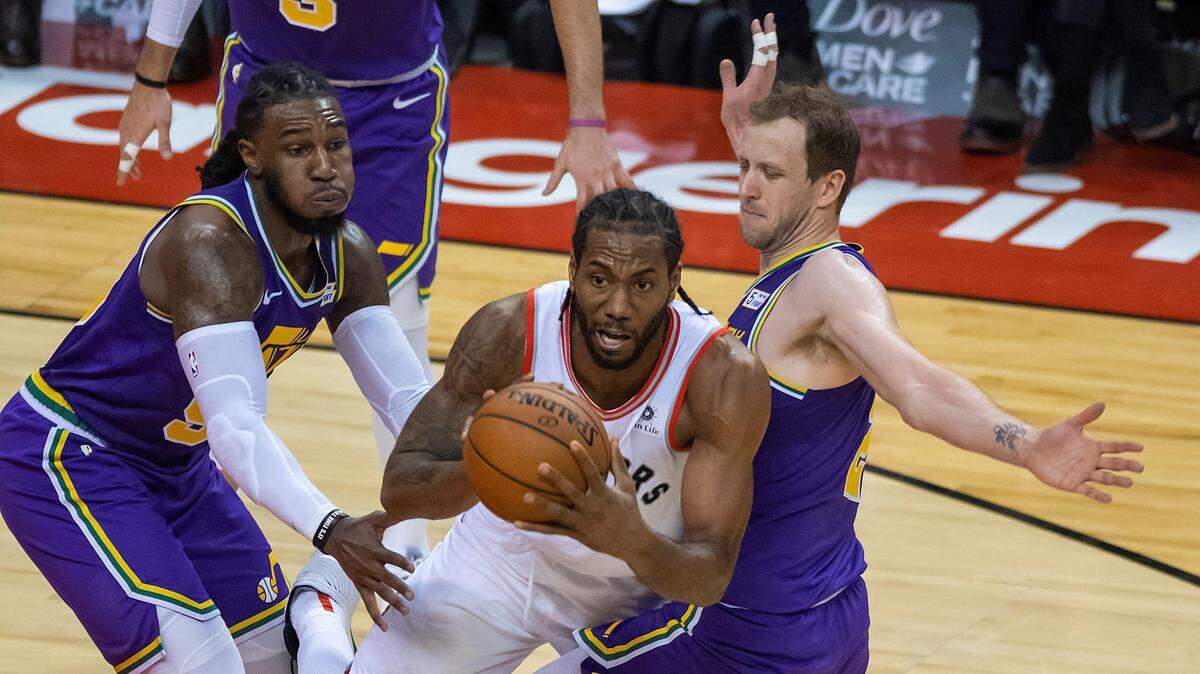 Kawhi Leonard (centro) trata de pasar el balón ante la marca de Jae Crowder (izq.) y Joe Ingles, en un partido entre los Raptors y el Jazz de Utah, celebrado el 1 de enero de 2019.