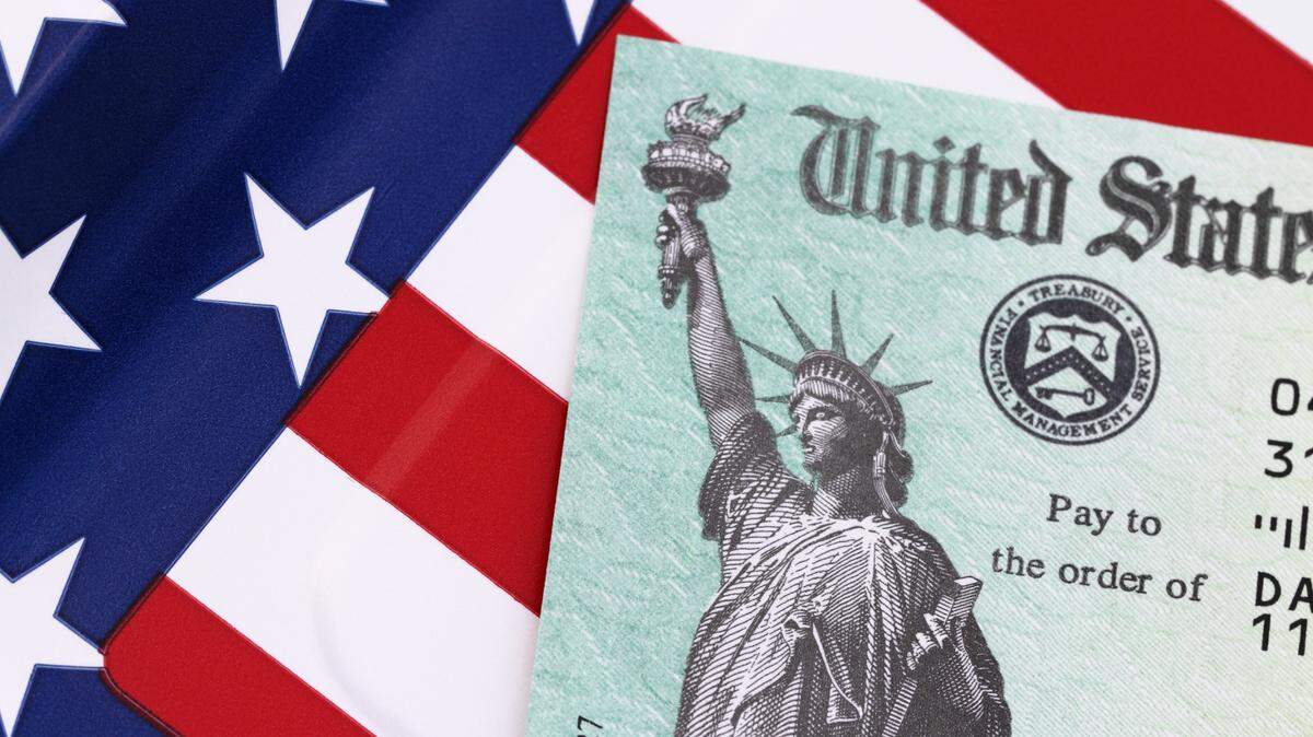 IRS tax refund check on a stars and stripes background. Check is showing the Treasury Seal and the Statue of Liberty.