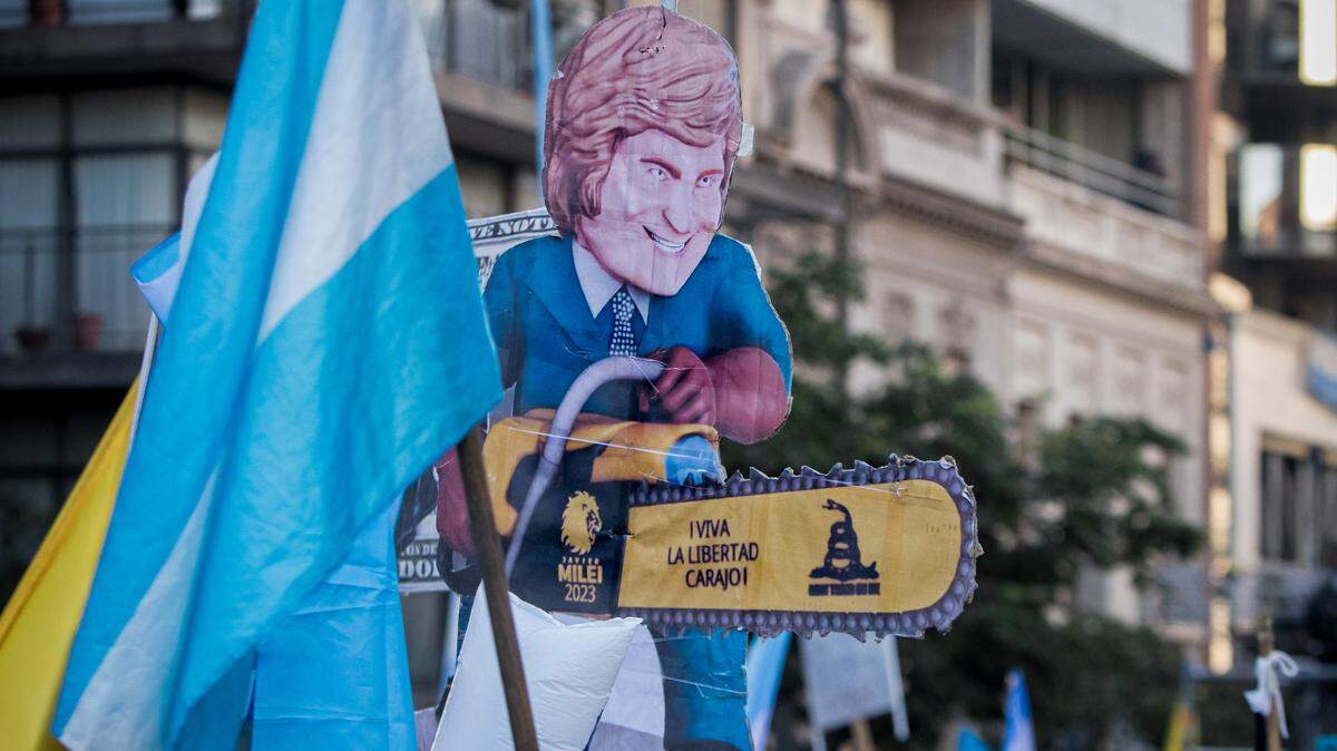 Un seguidor de Javier Milei marcha con una figura de cartón del político y el símbolo de su campana electoral: una motosierra, el 16 de noviembre de 2023, en Córdoba, Argentina. Tras ganar la presidencia, Milei ha tomado medidas radicales para reducir drásticamente el gasto público, al mismo tiempo que mantiene su popularidad.