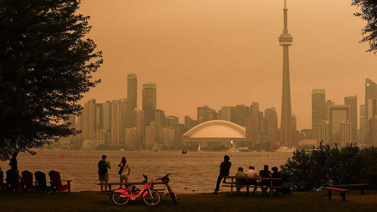 Personas contemplan el perfil urbano desde las Islas de Toronto mientras los incendios forestales del norte de Ontario provocan una mala calidad del aire en la ciudad, en Toronto, Ontario (Canadá), el 15 de julio de 2026. 