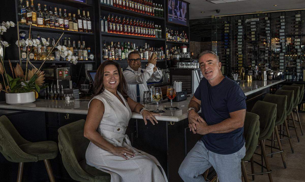 El barman Christian Pérez prepara bebidas para los propietarios Elizabeth y George Iglesias, en el bar de George’s en North Beach.