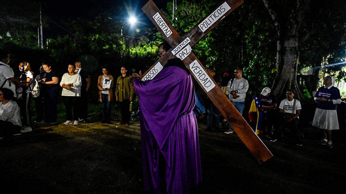 Un hombre carga una cruz mientras participa en una procesión de fieles católicos y familiares de presos políticos frente a la cárcel de El Rodeo, durante la Semana Santa en Guatire, estado Miranda, Venezuela, el miércoles, 1 de abril de 2026.