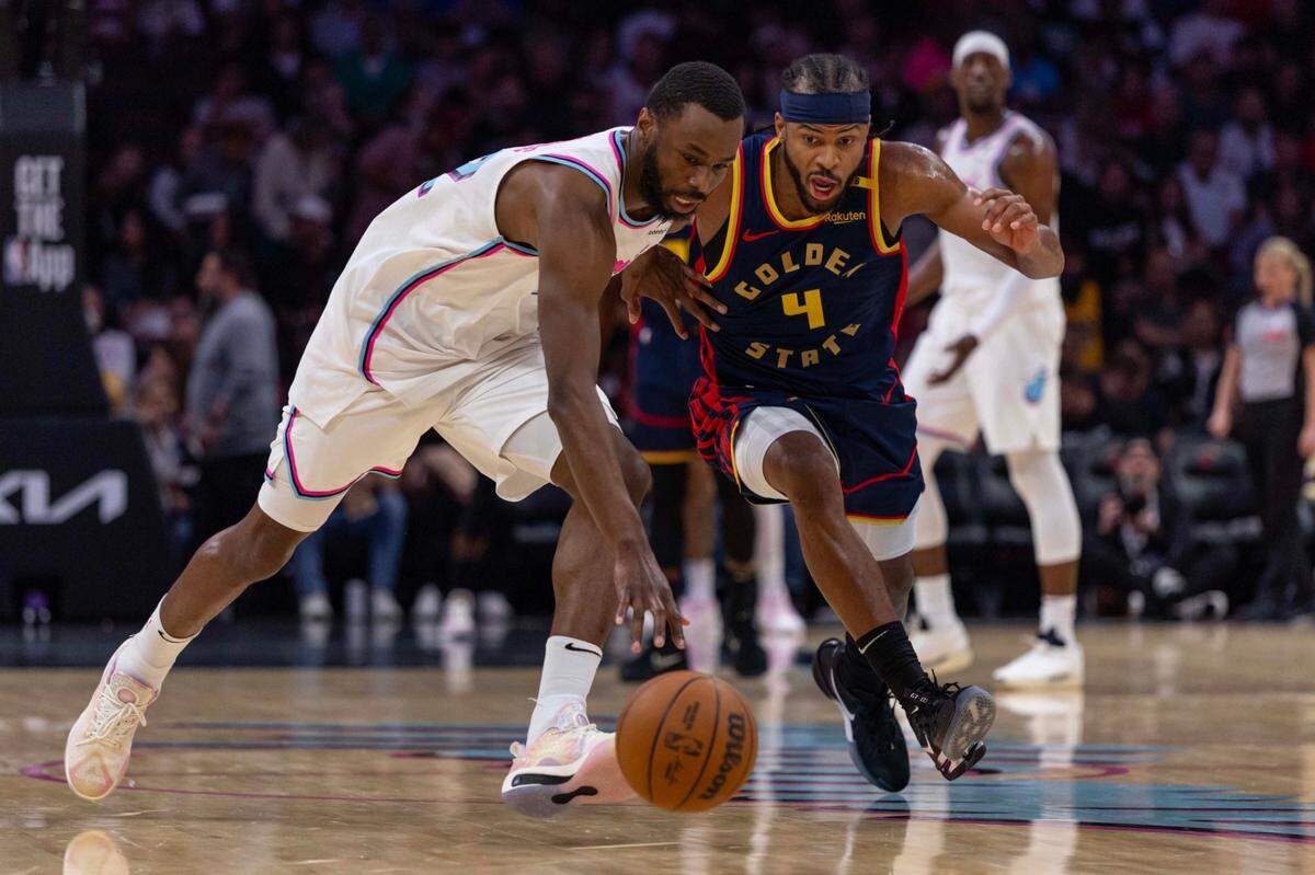 El jugador del Heat Andrew Wiggins (izq.) trata de recuperar el balón ante la marca de Moses Moody, de los Warriors de Golden State, en el partido celebrado el 25 de marzo de 2025 en Miami.