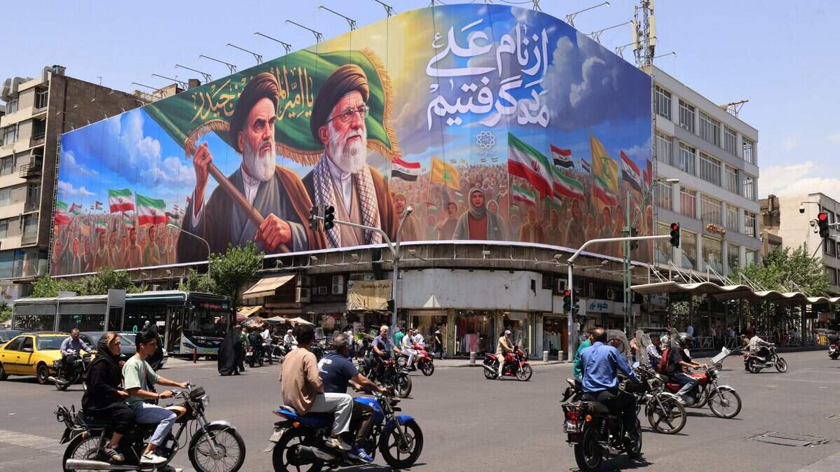 Personas circulan en motocicletas junto a una gran valla publicitaria con los retratos del fallecido líder supremo de Irán, el ayatolá Ruhollah Jomeini (izquierda), y del asesinado líder supremo, el ayatolá Ali Jamenei (derecha), en el centro de Teherán, el 8 de junio de 2026.