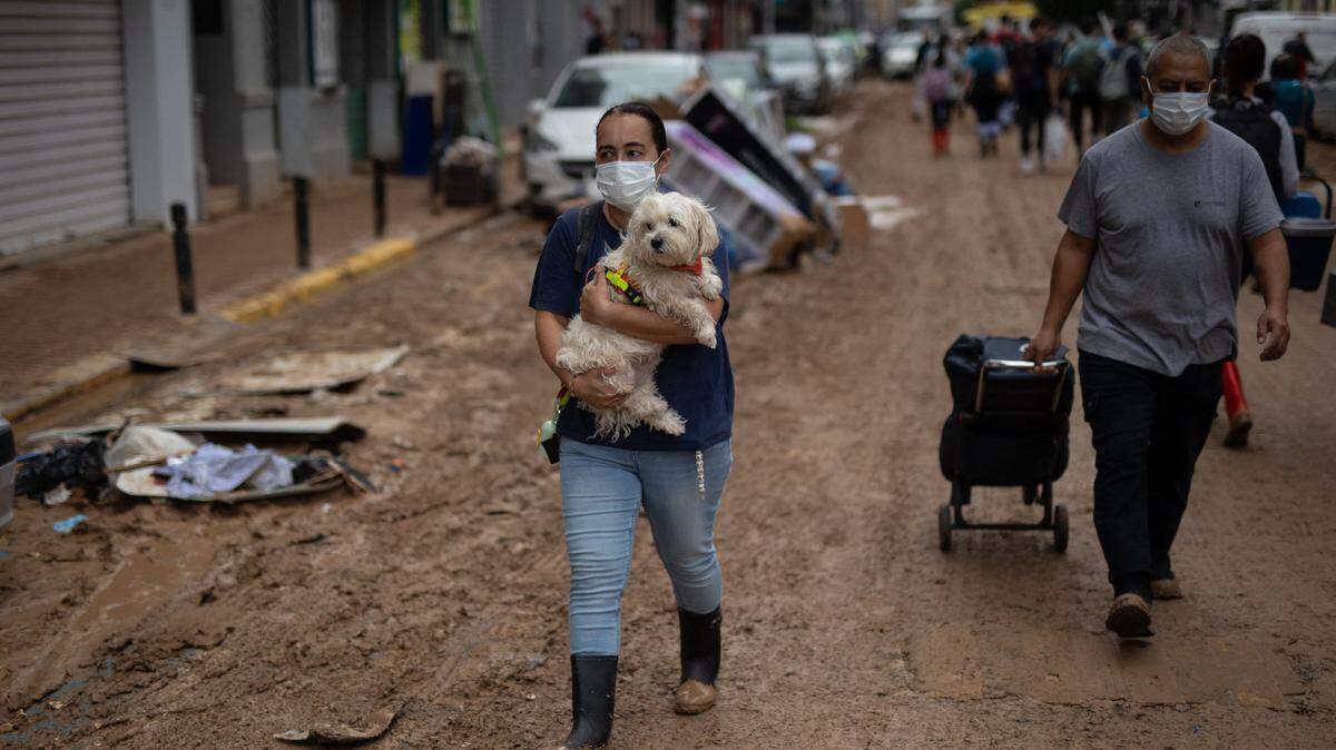Una mujer carga su mascota en una calle llena de barro por las inundaciones, en Benetússer, en la Comunidad Valenciana de España, el lunes 4 de noviembre de 2024.