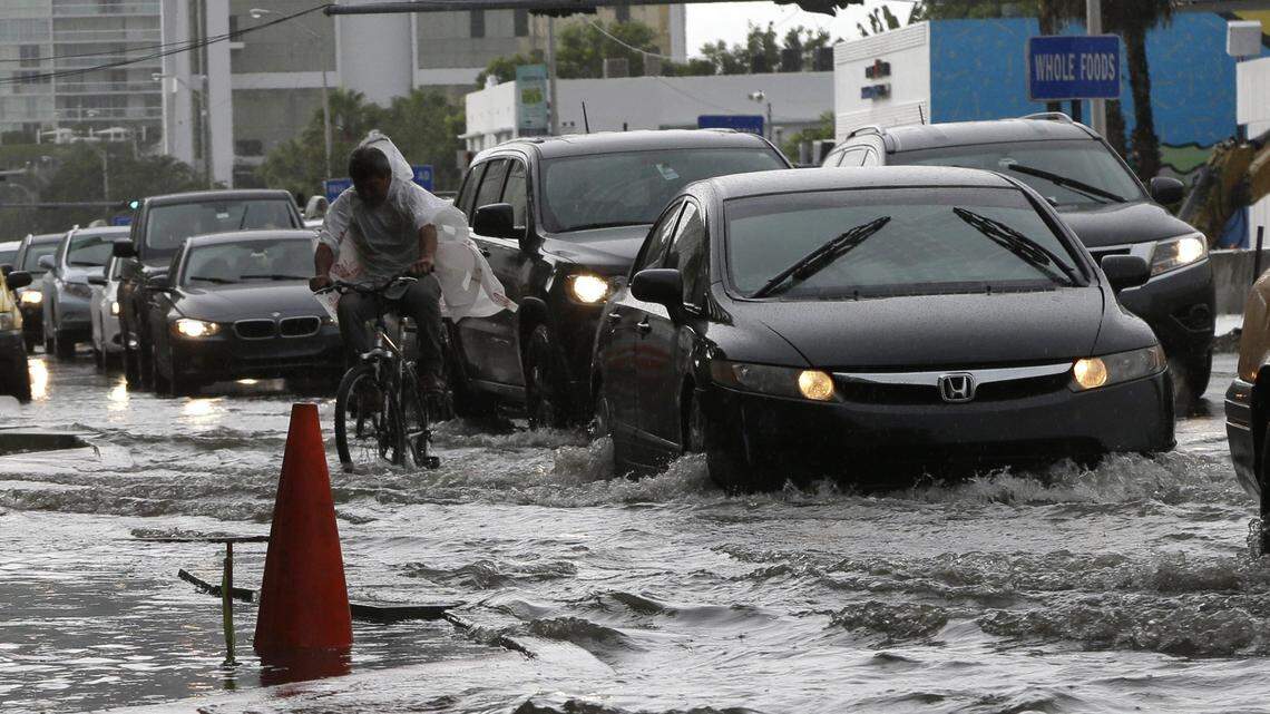 A bicyclist navigates through a Miami Beach street in September 2014. In the future, floods like these will be more common as seas rise, and experts predict it will impact the real estate market.