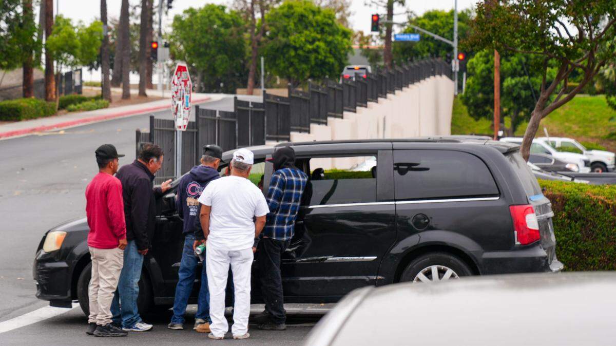 A group of men cluster around a vehicle in a Home Depot parking lot in Paramount, California, on June 9, 2025, several days after ICE raids sparked protests in the Los Angeles area. Some of the men said they are undocumented immigrants to the United States, and were risking detention and deportation if caught by ICE agents, but said they needed work.