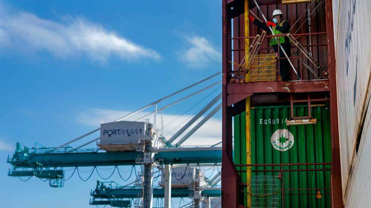 A crane unloads containers from a cargo ship at PortMiami.