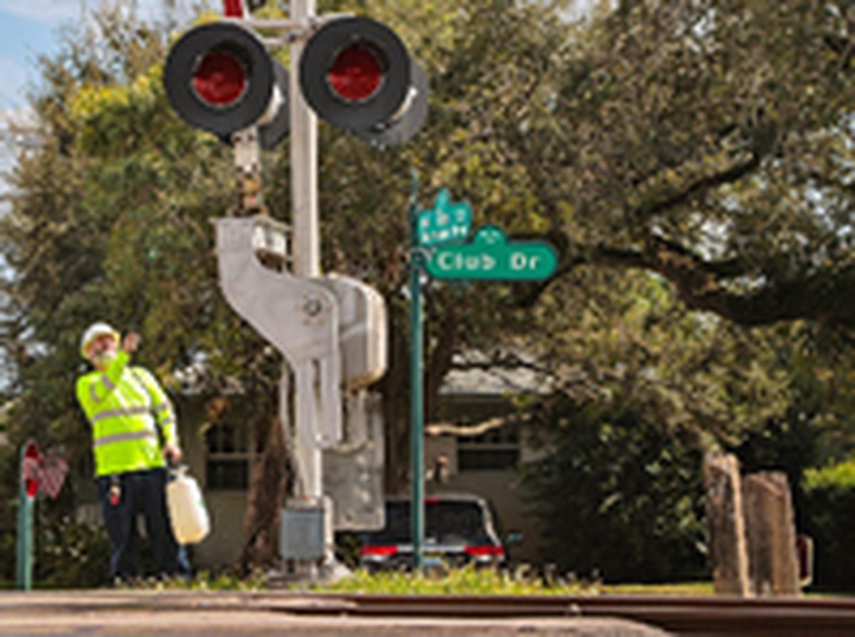 Un miembro del equipo de apoyo a la señalización limpia una luz de señalización en el corredor del tren Brightline en el paso a nivel de NE 96Street y Club Drive en Miami Shores el 7 de enero de 2022. Al Diaz ADIAZ@MIAMIHERALD.COM