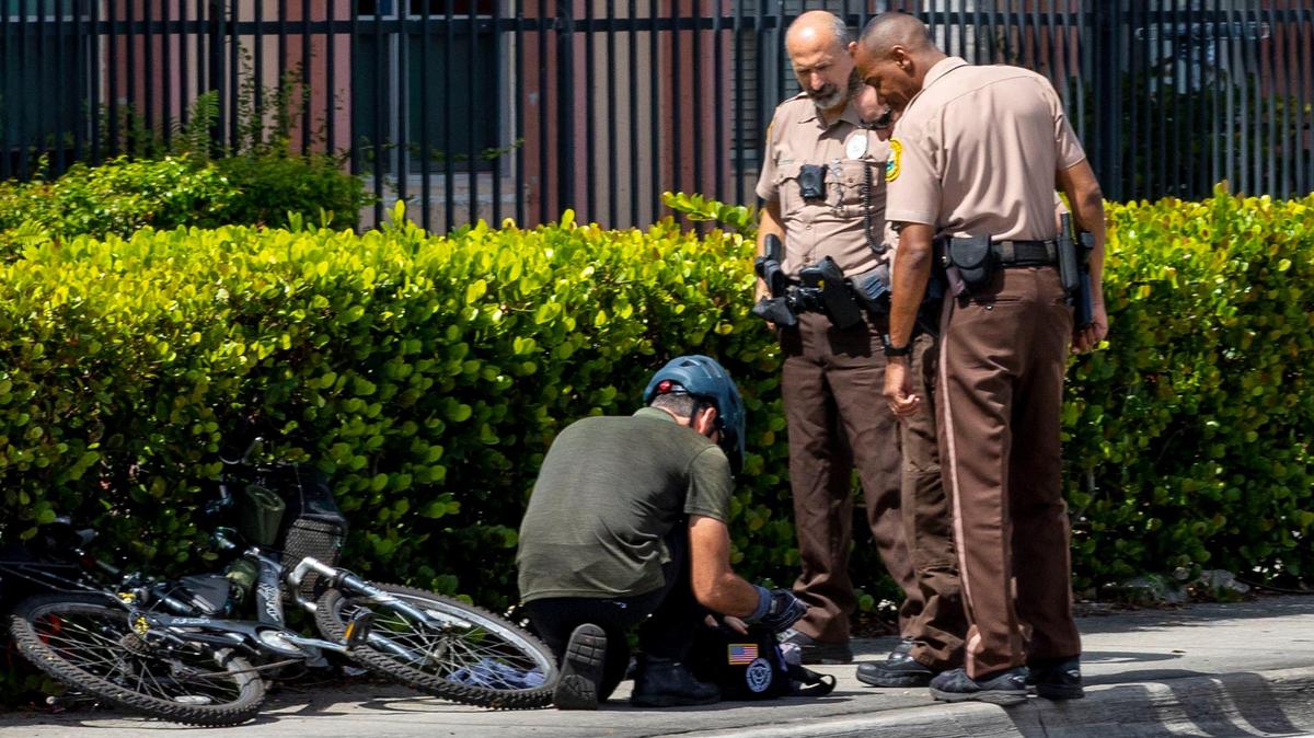 Agentes de la policía de Miami-Dade interactúan con un ciclista sospechoso mientras respondían a un posible incidente cerca del campus de Miami-Dade College Kendall, que provocó el cierre del campus, en Miami, Florida, el miércoles 17 de agosto de 2022.