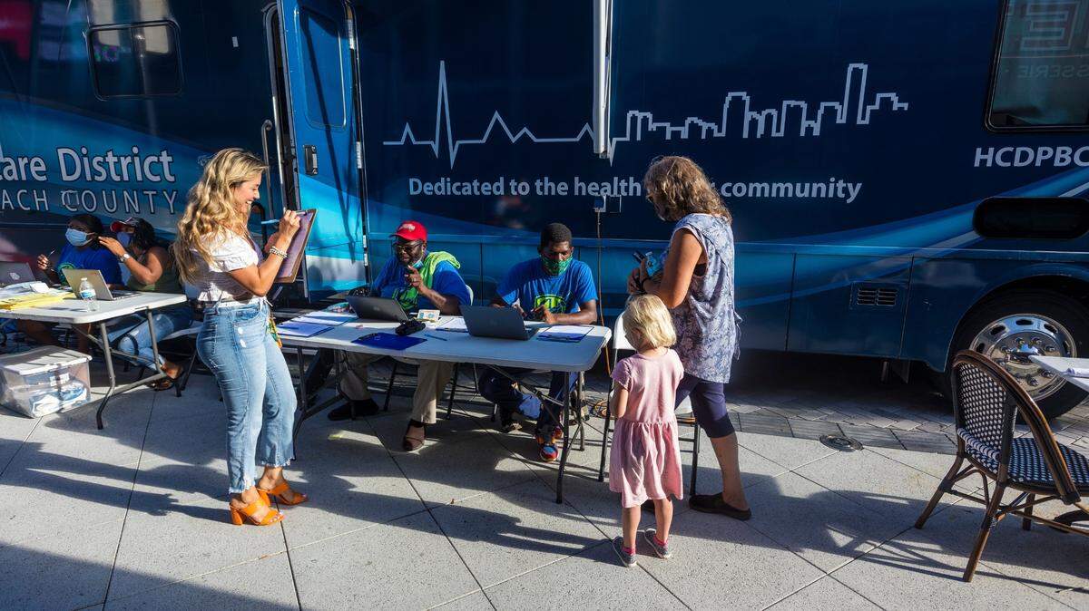 Varias personas visitan un centro móvil de vacunación contra el COVID en dowtown West Palm Beach, Florida, el 19 de agosto de 2021.