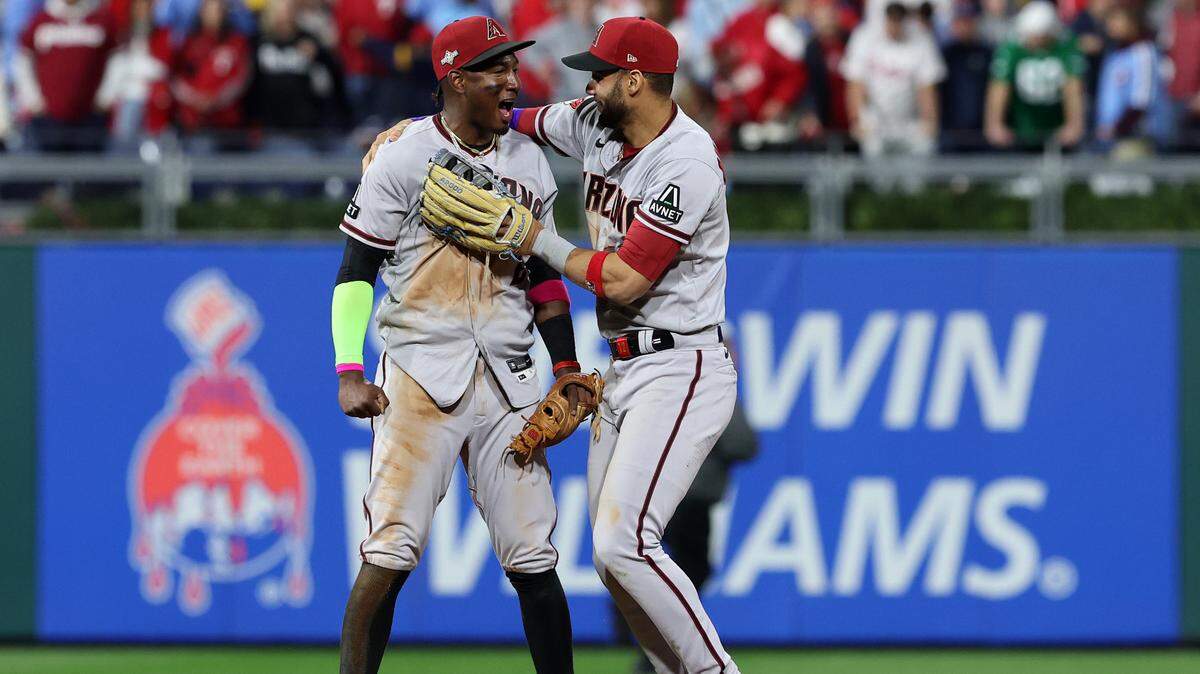 El jardinero de los Diamondbacks de Arizona Lourdes Gurriel Jr. (der.) festeja con el torpedero Geraldo Perdomo tras finalizar el séptimo partido de la Serie de Campeonato de la Liga Nacional que colocó a su equipo en la Serie Mundial, el 24 de octubre de 2023 en Filadelfia. 