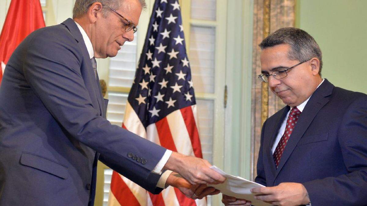 Jeffrey DeLaurentis (izq.), jefe de la sección de intereses de EEUU en Cuba, le entrega una carta del presidente  Barack Obama a Marcelino Medina, el viceministro de relaciones exteriores de Cuba, el miércoles 1ro de julio en La Habana. Ambos países han acordado abrir sus embajadas el 20 de julio. 