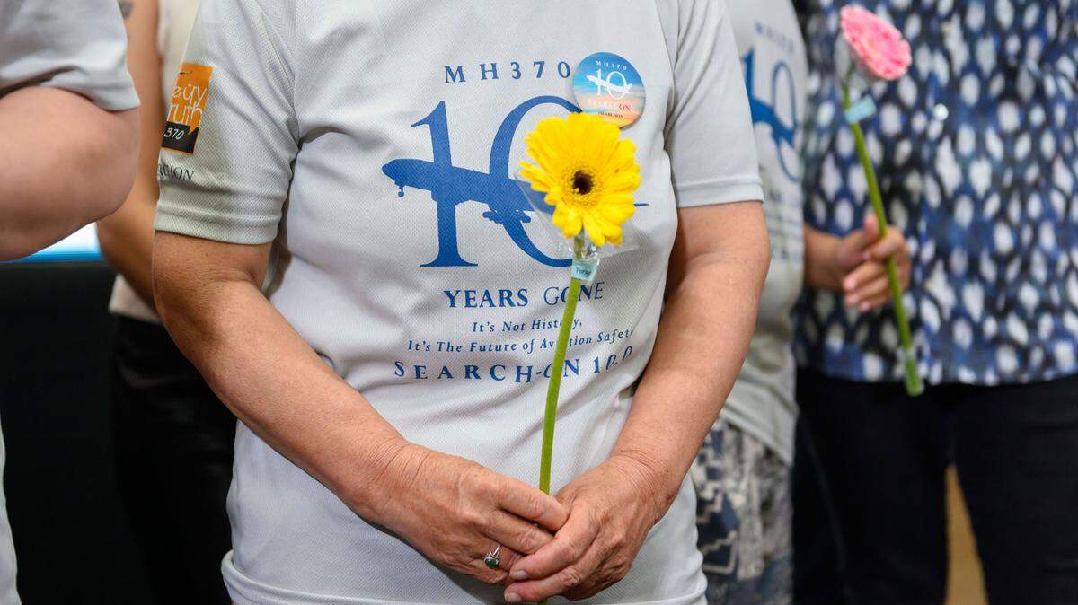 Gente sostiene flores en un evento que marca el décimo año desde la desaparición del MH370 en Subang Jaya, estado de Selangor, Malasia, 3 de marzo de 2024.