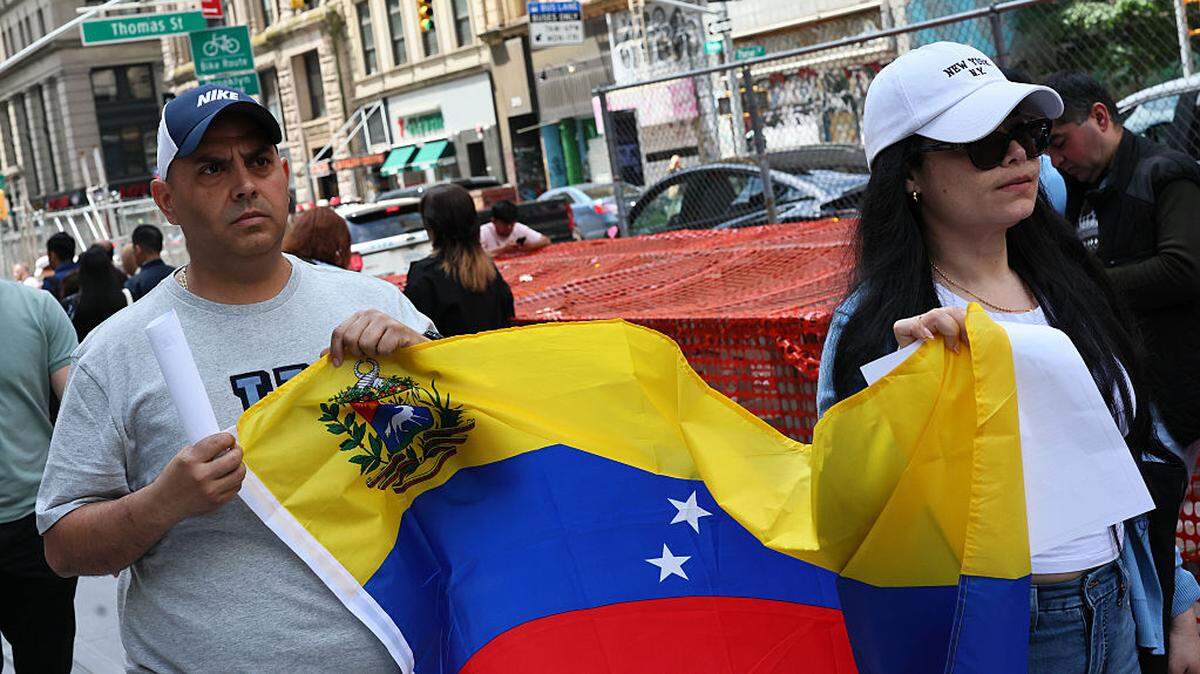 Varias personas portan una bandera venezolana mientras pasan junto a otras personas que esperan para entrar al tribunal de inmigración en Federal Plaza, en la ciudad de Nueva York, el 8 de mayo de 2025.
