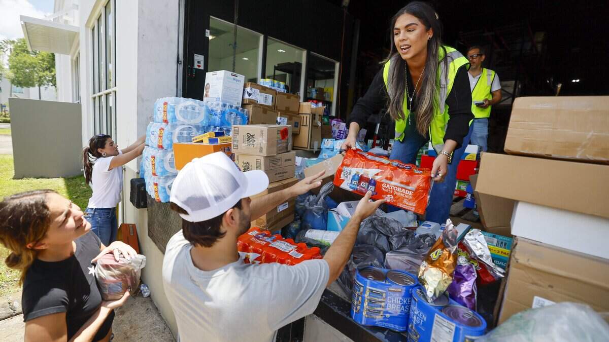Ariana Guerrero, voluntaria de Global Empowerment Mission (centro), recibe suministros donados por Joaquín Herrera y Paola Pisana para los damnificados por los terremotos en Venezuela, el 25 de junio de 2026 en Doral, Florida.