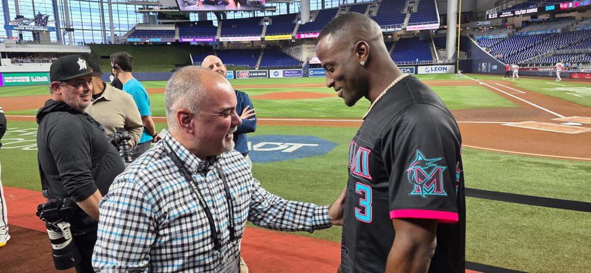 El cubano Adeiny Hechavarría lanzó la primera bola en Miami el miércoles en el partido contra los Nacionales de Washington. En la foto junto a Juanito Martínez, jefe de mercadeo hispano de los Marlins.
