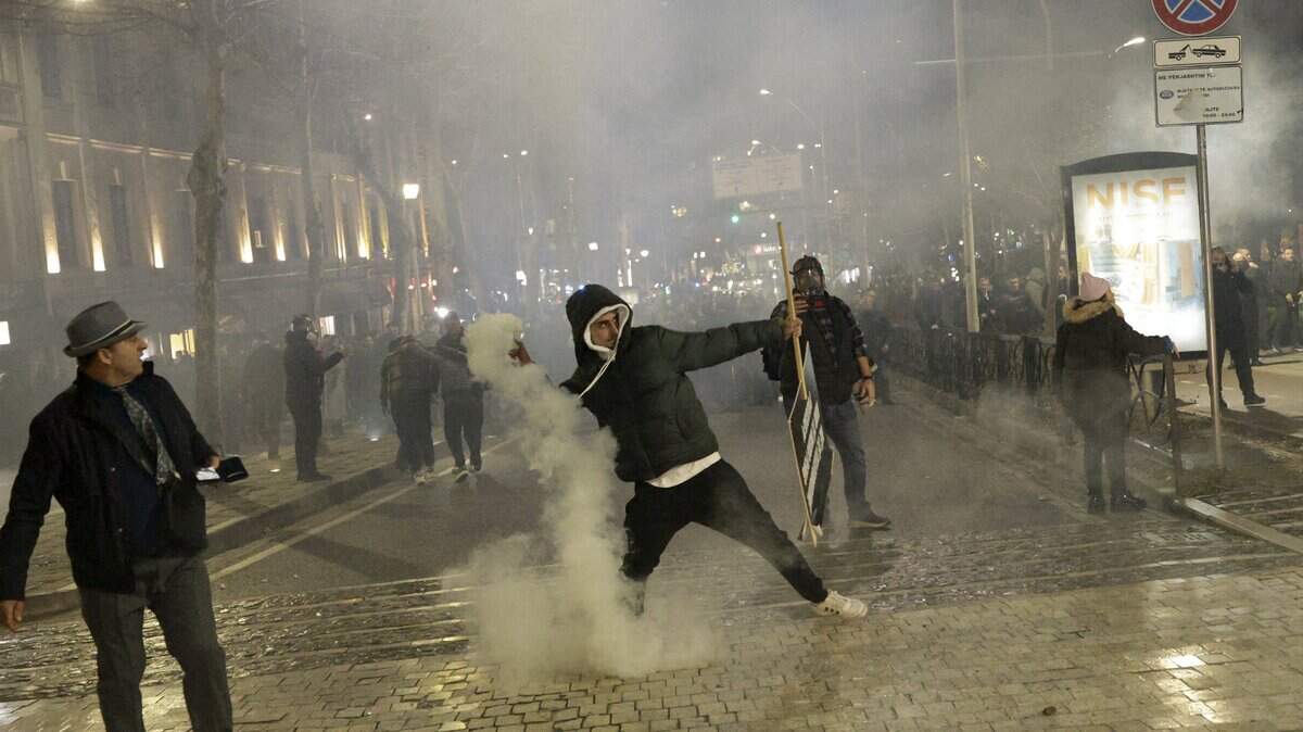 Un manifestante devuelve un bote de gas lacrimógeno durante enfrentamientos con la policía frente al edificio del Parlamento durante una protesta antigubernamental en Tirana el 24 de enero de 2026.
