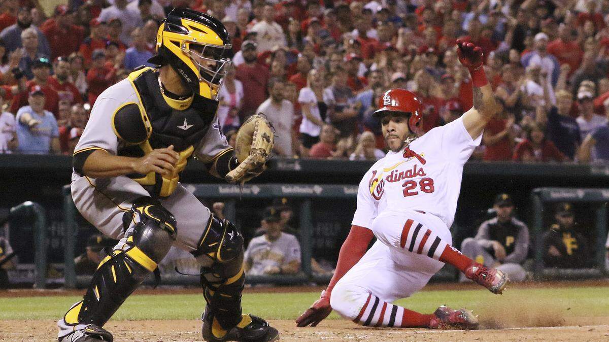Tommy Pham de los Cardenales de San Luis anota tras pasar al receptor de los Piratas de Pittsburgh Elías Díaz en la séptima entrada de un partido de béisbol el domingo 25 de junio de 2017 en St. Louis.