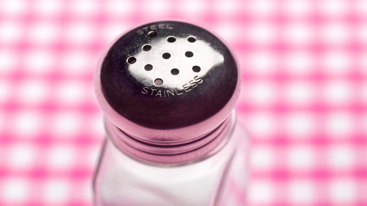 Close up of a salt shaker on a table with gingham tablecloth