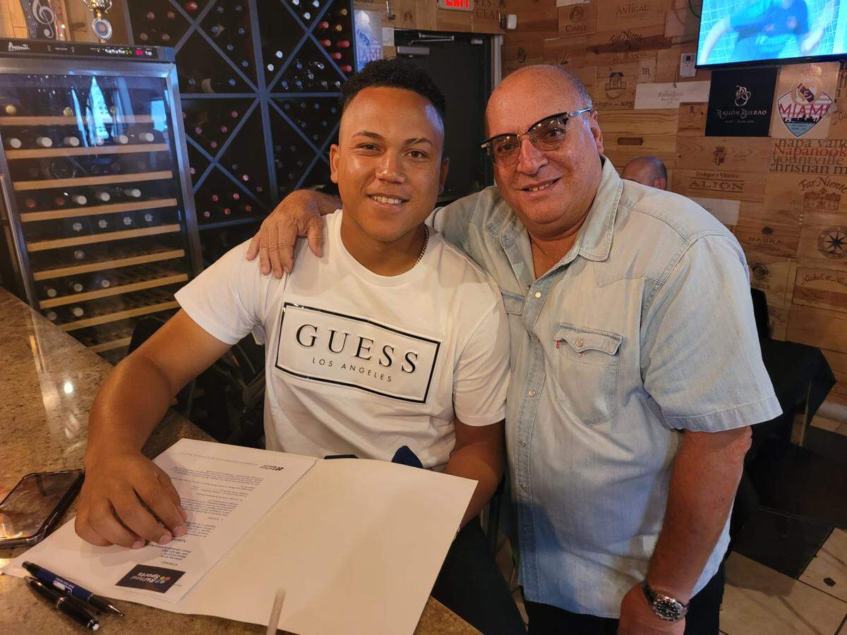 El exlanzador de Industriales firmó este sábado la documentación que le convierte en miembro de la franquicia de los Rangers, al lado de su agente Carlos Pérez.