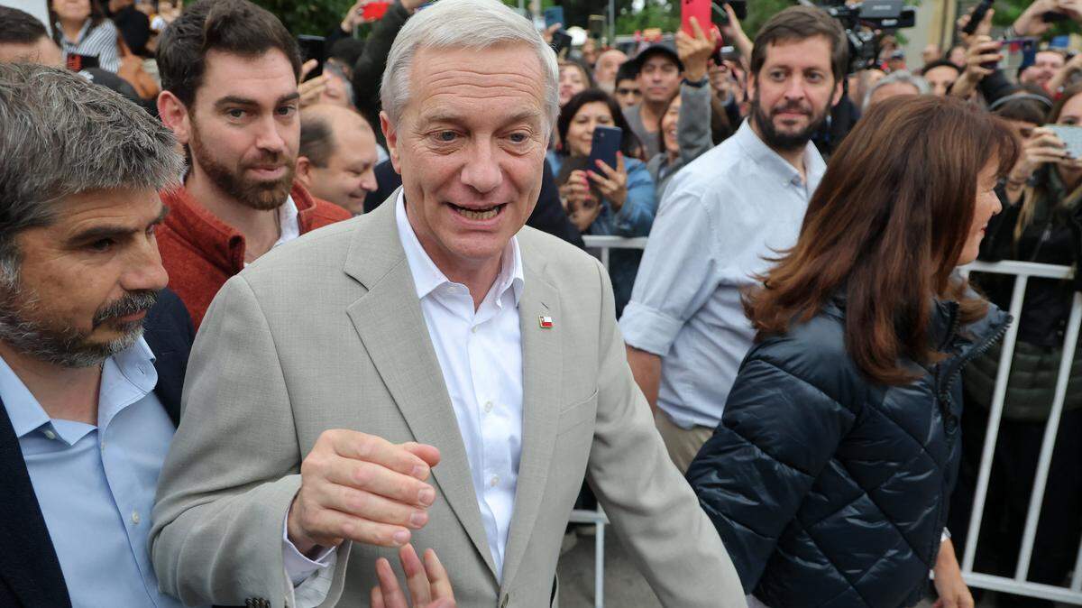 Chile's presidential candidate Jose Antonio Kast (C), of the Partido Republicano party, greets supporters next to his wife Maria Pia Adriasola (R) outside a polling station after casting his ballot during the presidential runoff election in Paine, south of Santiago, on December 14, 2025. Chileans head to the polls for a presidential runoff between Jeannette Jara, a communist backed by a broad left coalition, and Jose Antonio Kast, a devout far-right politico promising a hard line on security and migration. (Photo by Javier TORRES / AFP via Getty Images)